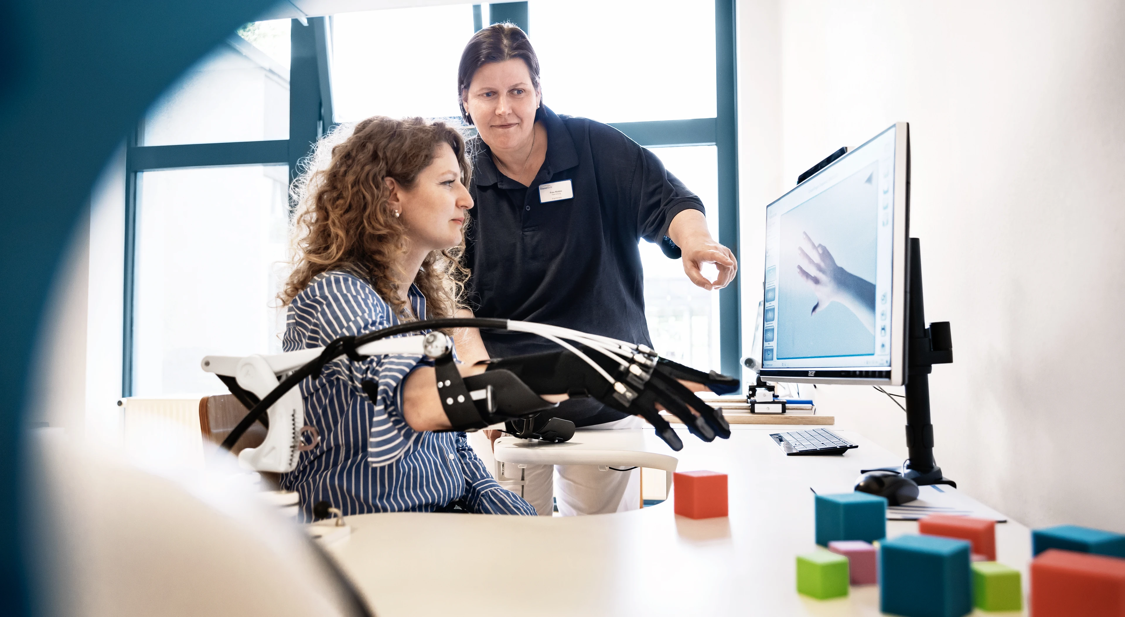 Eine Ergotherapeutin hilft einer jungen Patientin im Handlabor zu trainieren.