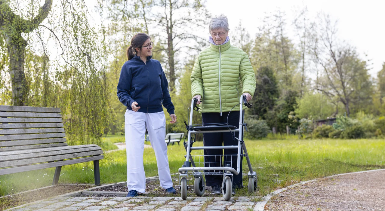 Eine Pflegekraft übt mit einer Patienten das Fahren mit dem Rollator im Rollator-Parcour.