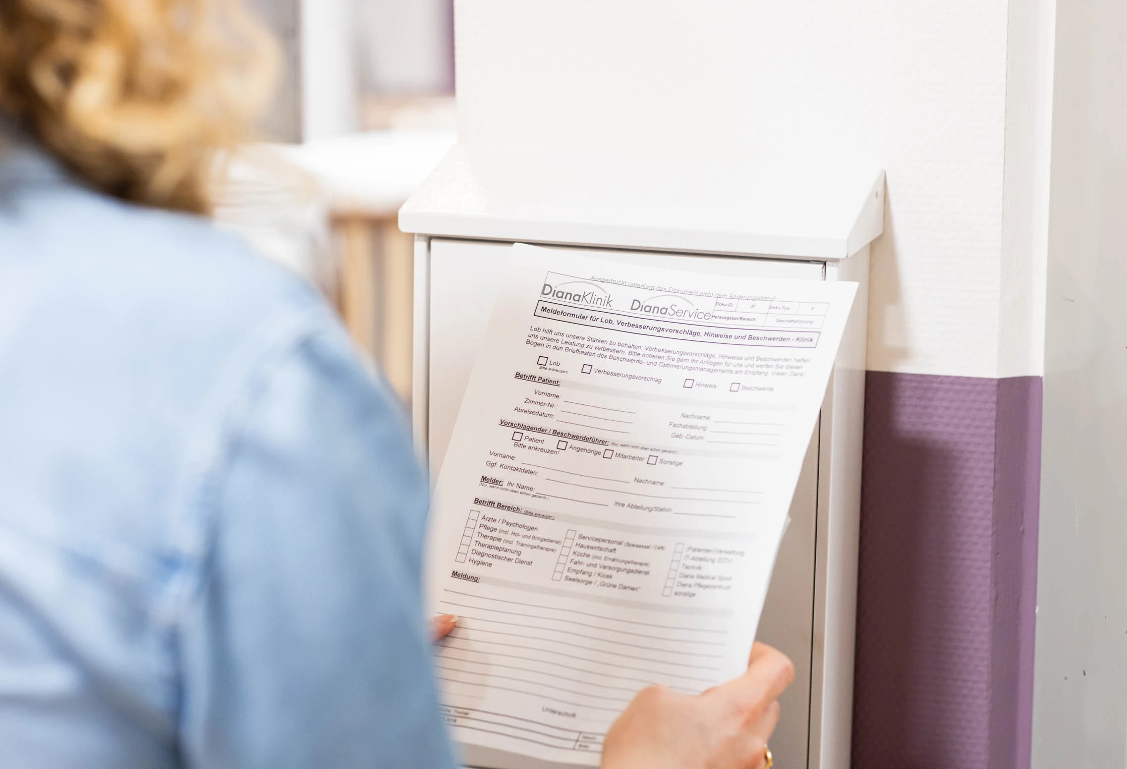 Eine Patientin hält einen Fragebogen für Lob, Verbesserungsvorschlägen, Hinweisen und Beschwerden in den Händen.