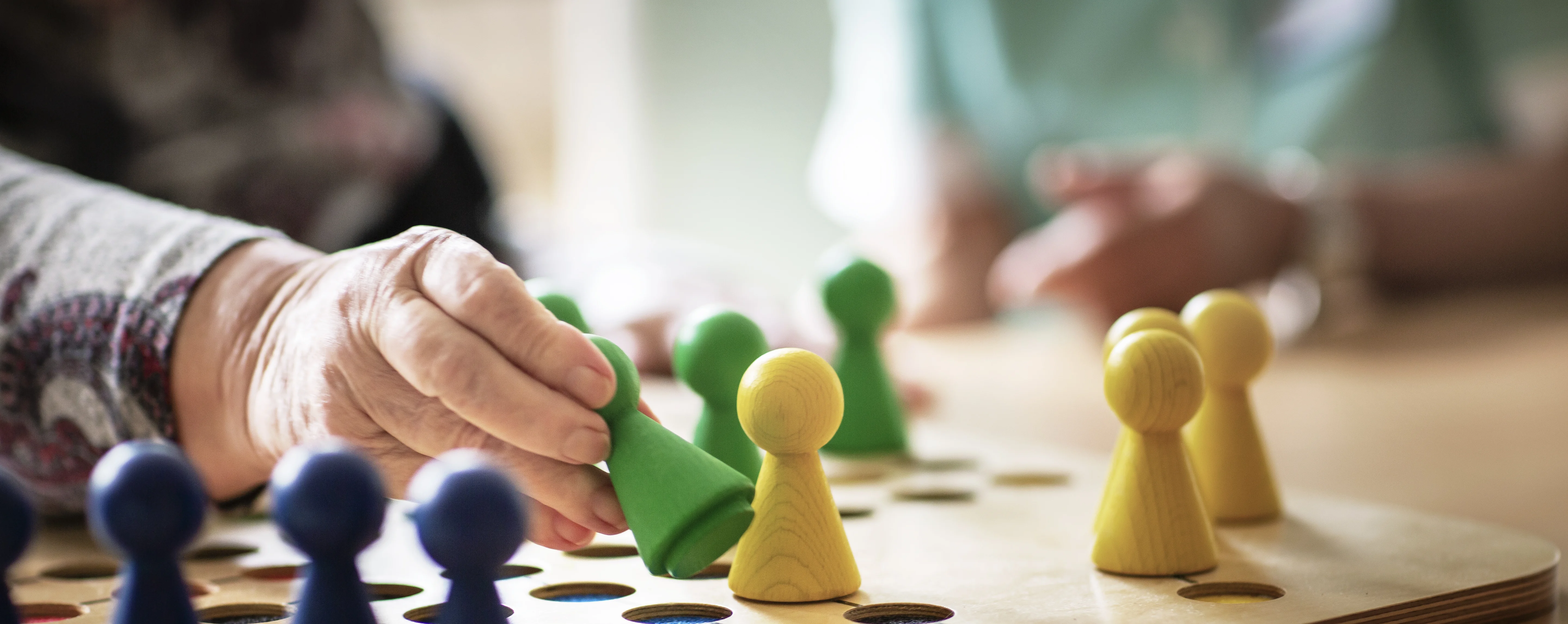 Ein ehrenamtlicher Mitarbeiter spielt mit einem Patienten ein Brettspiel.