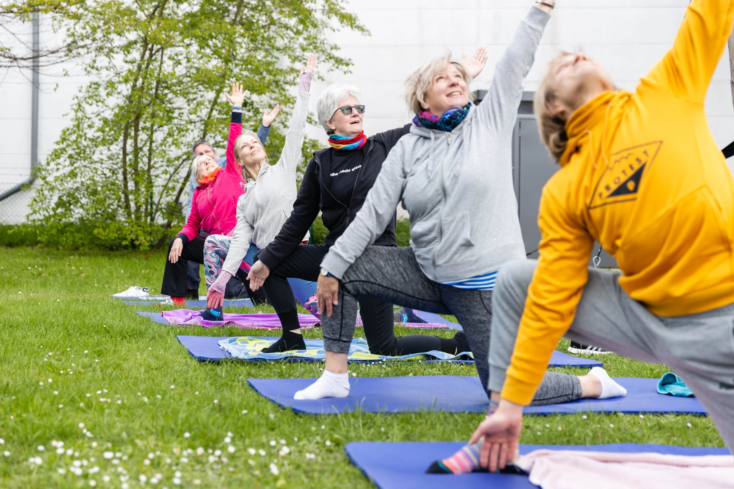DianaKlinik | Ganzheitlicher Ansatz Rehapatienten machen draußen im Grünen Übungen auf der Matte.