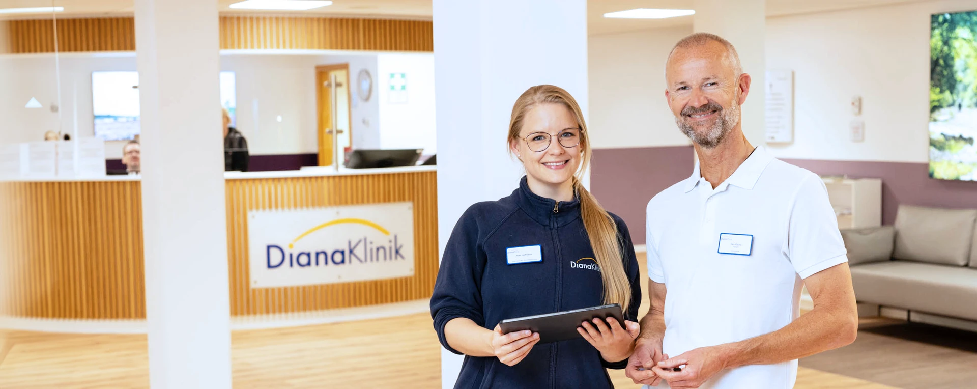 DianaKlinik | Foyer Eine Pflegekraft und ein Arzt im Foyer der DianaKlinik. Beide schauen freundlich in die Kamera.
