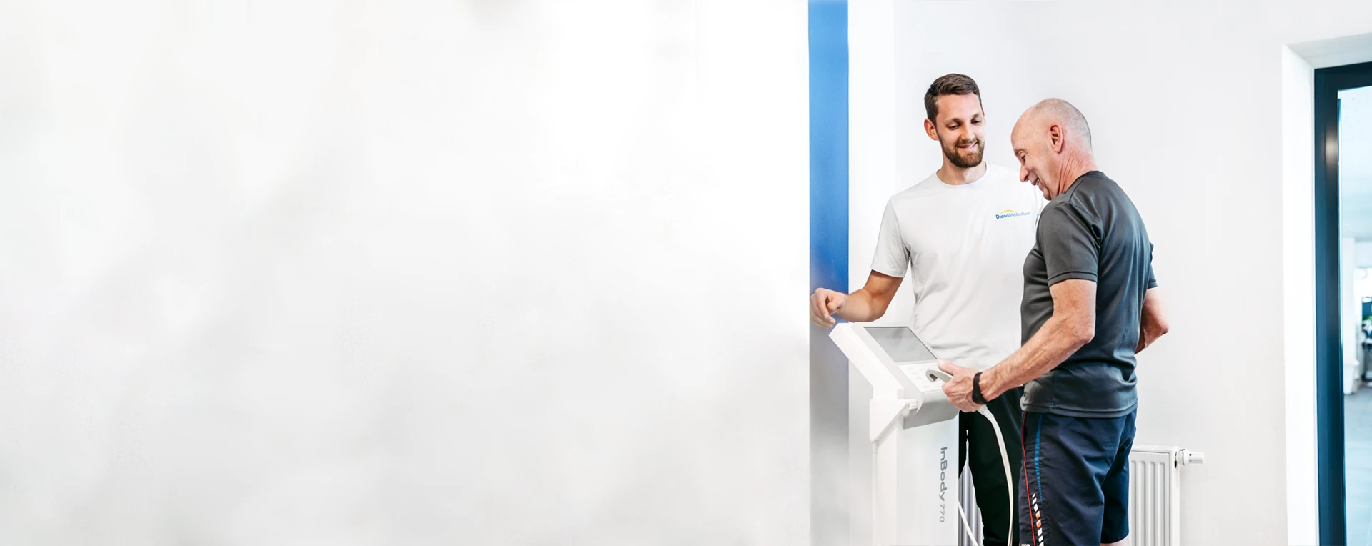 Ein Sporttherapeut von DianaMedicalSport erläutert einem älteren Mitglied die Daten auf der Körperanalysewaage.