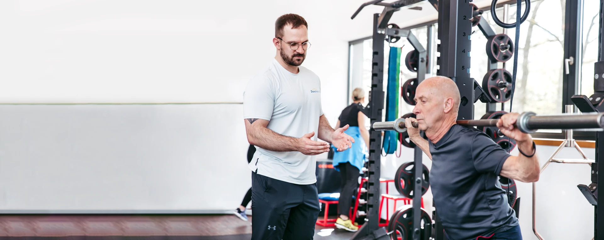 Ein Sporttherapeut leitet ein Mitglied des DianaMedicalSport beim Training an.