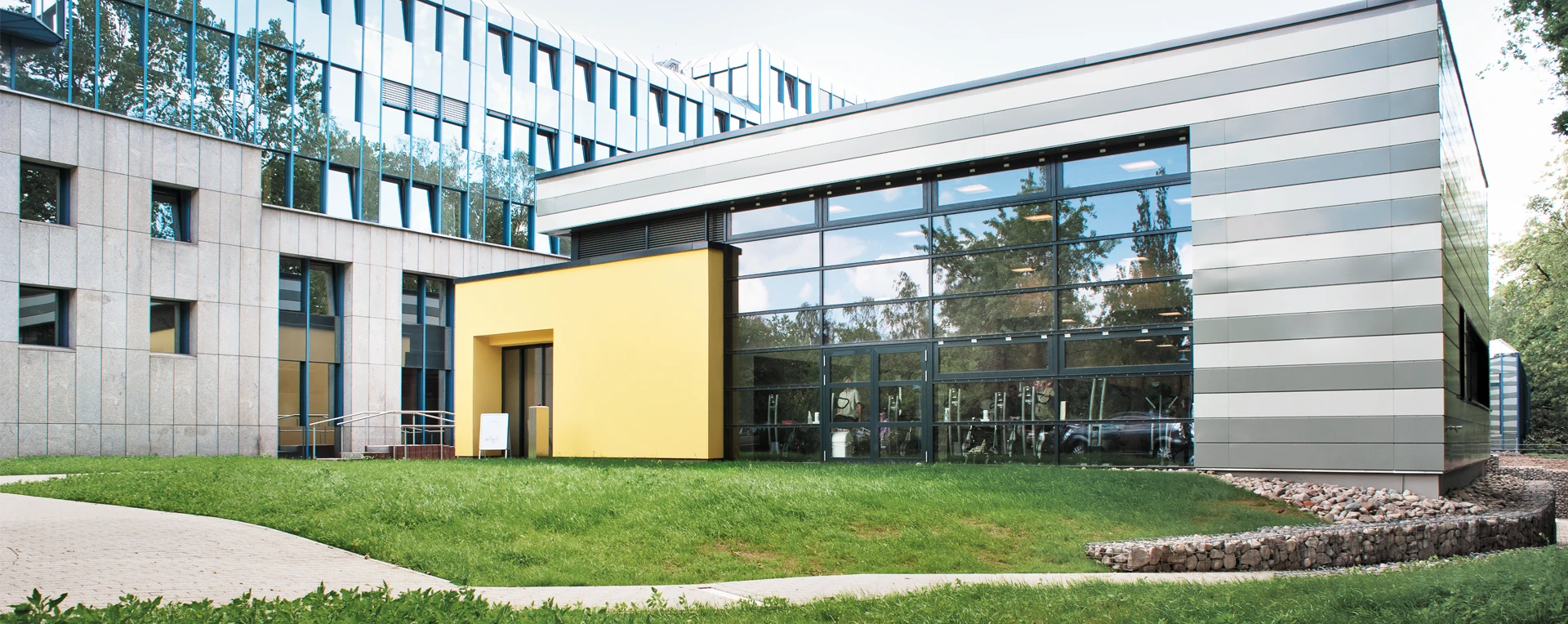 Außenansicht des DianaMedicalSport-Gebäudes mit großer Glasfassade und gelbem Eingangsbereich